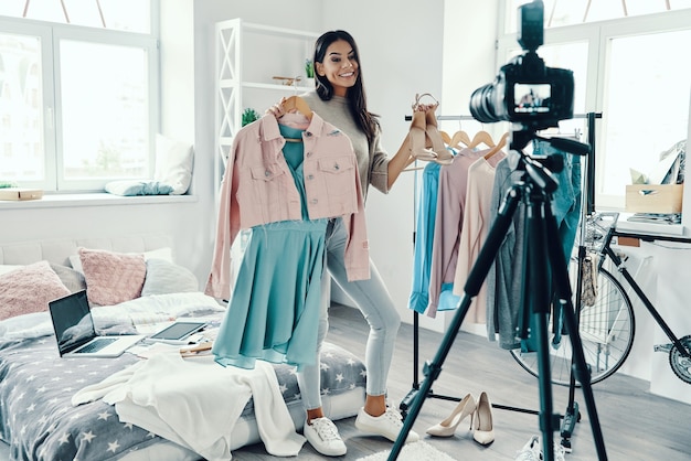 Toute la longueur de la belle jeune femme en vêtements décontractés faisant une vidéo sur les réseaux sociaux tout en passant du temps à la maison