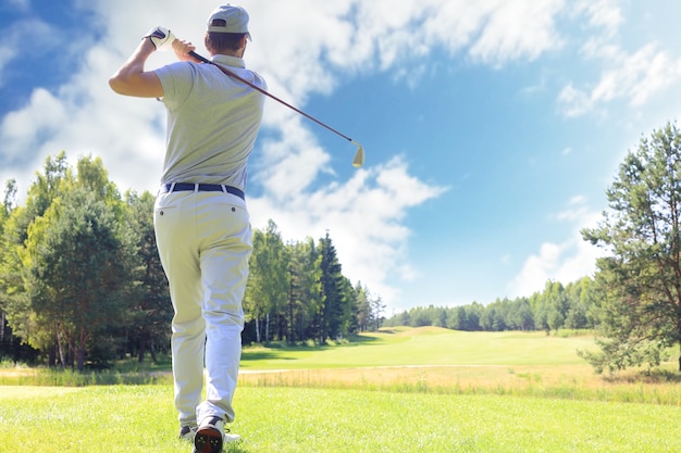 Toute la longueur du joueur de golf jouant au golf par beau temps. Golfeur masculin professionnel tirant sur le terrain de golf.