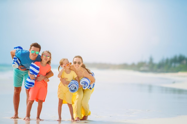 Photo toute la longueur d'une famille joyeuse debout sur la plage