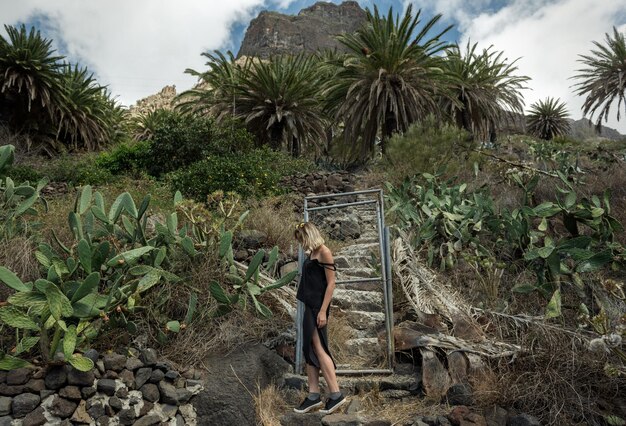 Photo toute la longueur d'une femme debout à côté d'un arbre contre le ciel