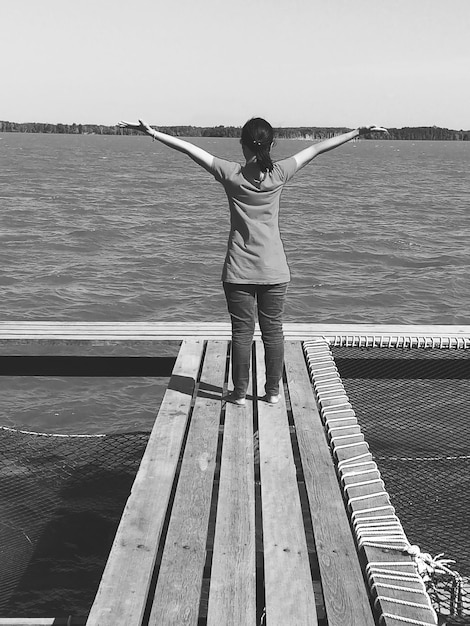 Toute la longueur d'une femme debout par la mer contre le ciel