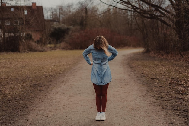 Toute la longueur d'une femme debout sur une route de terre