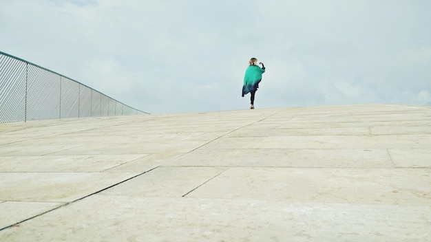 Toute la longueur d'une femme marchant sur un pont contre le ciel
