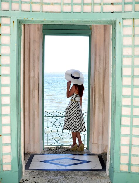 Photo toute la longueur d'une femme portant un chapeau vue à travers la porte