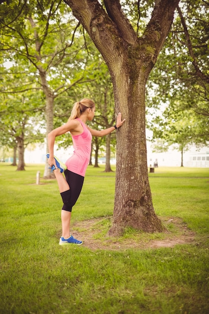 Photo toute la longueur de la femme qui exerce avec une jambe qui s'étend