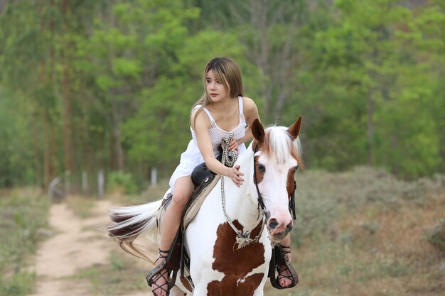 Toute La Longueur De La Femme En Robe à Cheval Sur Le Terrain Par Des Arbres Contre Le Ciel