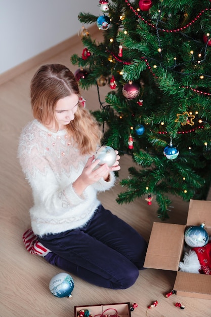 Toute la longueur de la fille décorant l'arbre de Noël