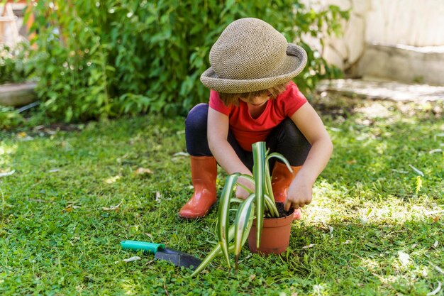 Photo toute la longueur de la fille tenant un chapeau sur l'herbe dans la cour