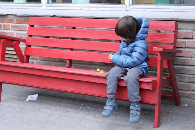 Photo toute la longueur d'un garçon assis sur un banc