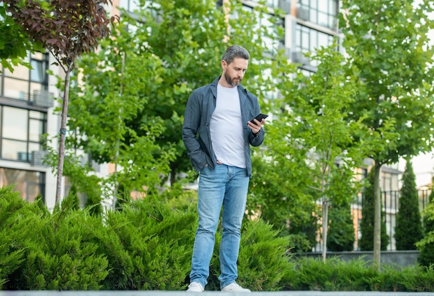 Toute la longueur de l'homme bavardant au téléphone homme en plein air bavardant au téléphone dans la rue