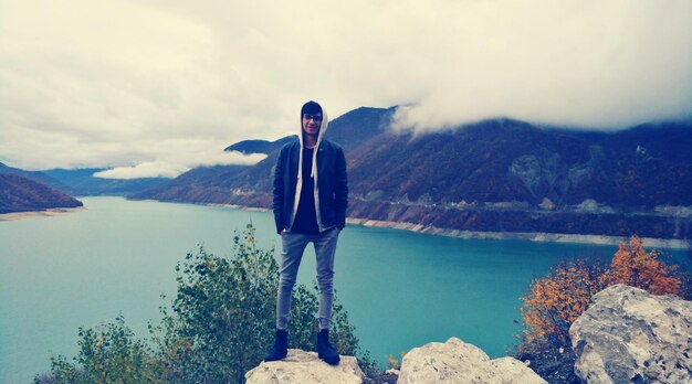 Toute la longueur de l'homme debout sur le rocher contre le lac et les montagnes