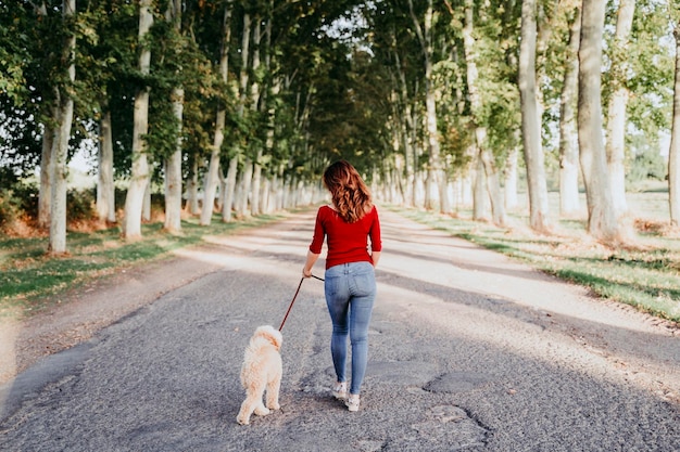 Toute la longueur d'un homme marchant avec un chien sur la route