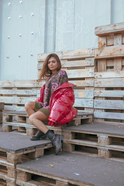 Toute la longueur d'une jeune femme portant une veste rouge alors qu'elle est assise en ville