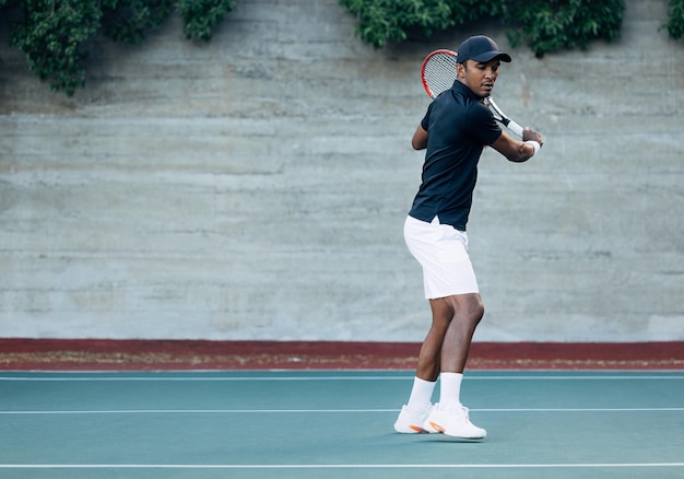 Toute la longueur d'un joueur de tennis masculin debout sur un terrain dur pendant un match