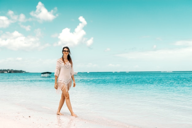 Toute la longueur de la magnifique femme de race blanche en robe d'été posant sur une plage.