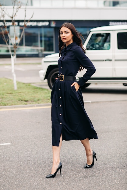 Sur toute la longueur de la magnifique jeune femme brune marchant dans la rue dans sa longue robe bleu foncé