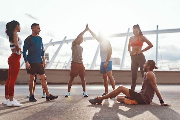 Toute la longueur des personnes en vêtements de sport s'encourageant pendant l'exercice à l'extérieur