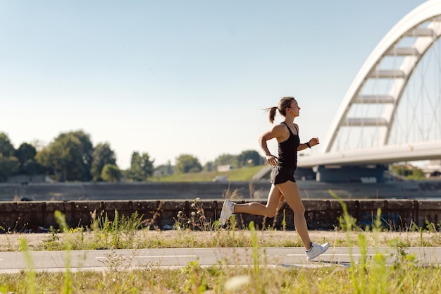 Toute la longueur de la sportive faisant du jogging le long d'une berge