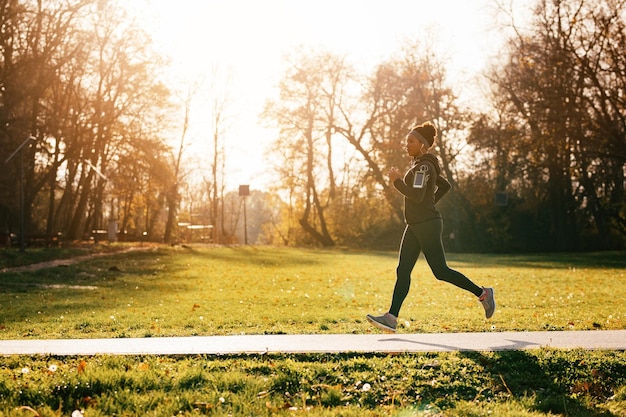 Toute la longueur de la sportive noire faisant du jogging dans la nature Espace de copie