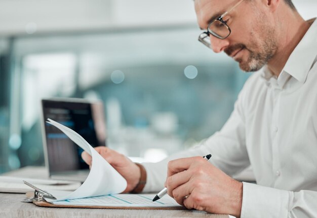 Toutes les finances de l'entreprise semblent être en ordre Photo d'un homme d'affaires mature assis seul dans son bureau et calculant ses finances