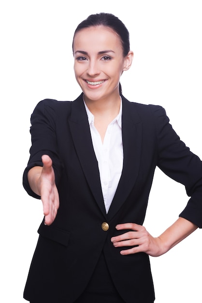 Toutes nos félicitations! Jeune femme confiante en tenue de soirée tendant la main pour secouer et sourire en se tenant debout isolée sur blanc