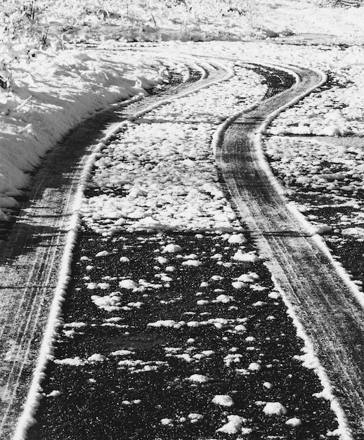 La trace des pneus sur une route enneigée, une photo monochrome en noir et blanc