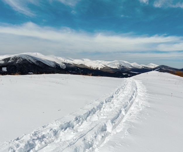 Photo trace de traîneau et empreintes de pas au sommet d'une colline de montagne en hiver