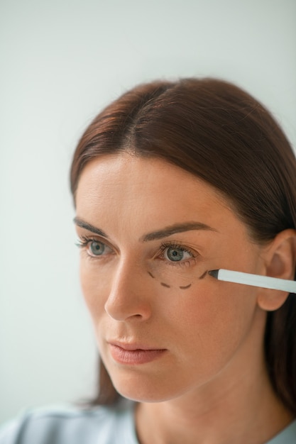 Tracer des lignes. Chirurgien plasticien dessinant des lignes sur le visage des clients