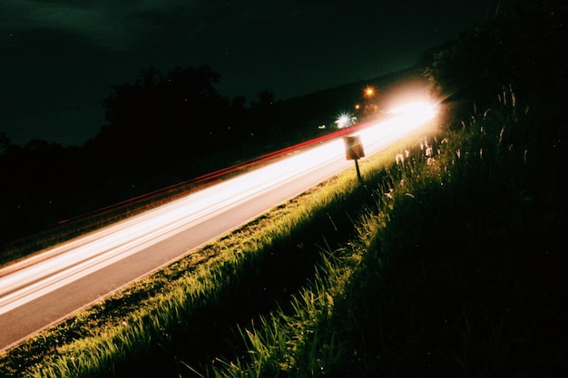 Photo des traces de lumière sur la route la nuit.