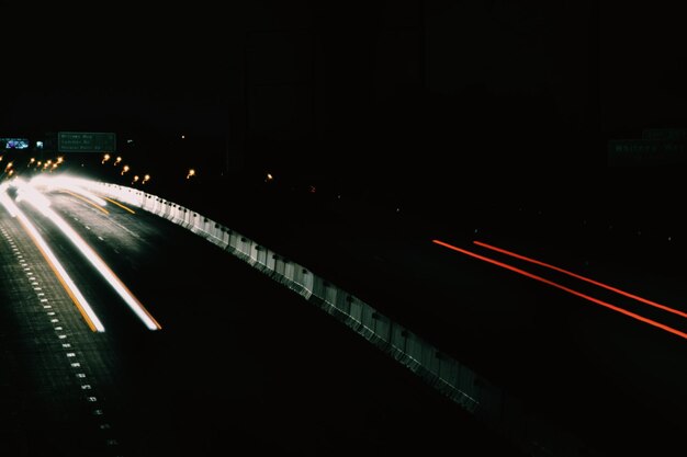 Photo des traces de lumière sur la route la nuit.
