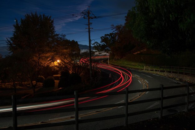 Photo des traces de lumière sur la route la nuit.