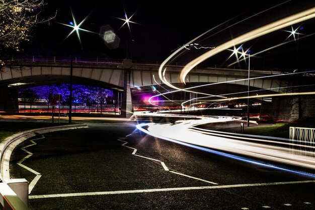 Photo des traces de lumière sur la route la nuit.