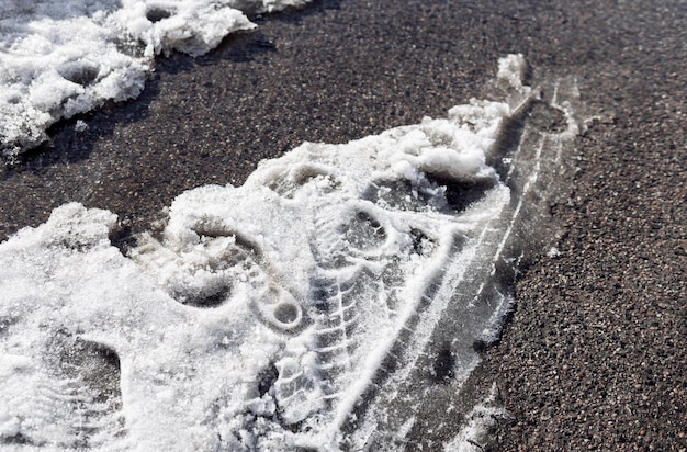 Traces de pneus de voiture sur la neige fondue le début du printemps et la fonte des neiges