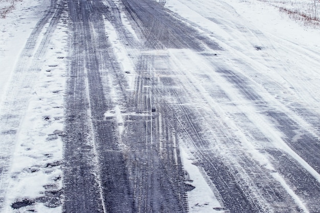 Traces de roues de voiture sur une route enneigée