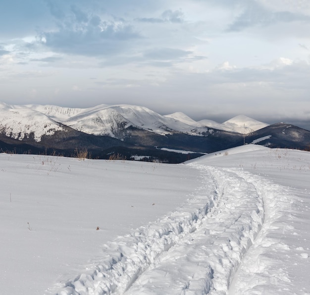 Photo traces de traîneau et empreintes de pas sur le sommet d'une colline d'hiver