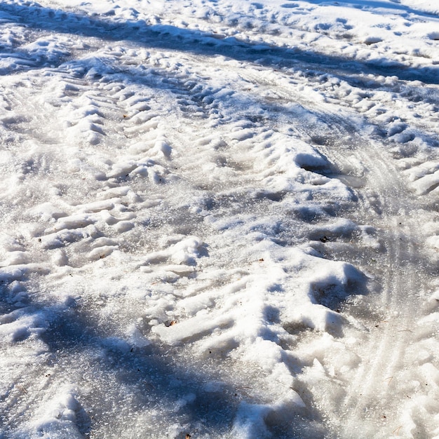 Traces de voitures gelées sur une route de campagne enneigée