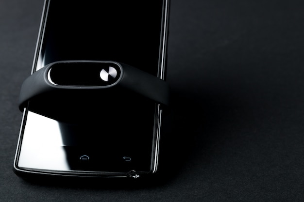Tracker de remise en forme et smartphone sur fond noir. Bracelet de sport et smartphone.