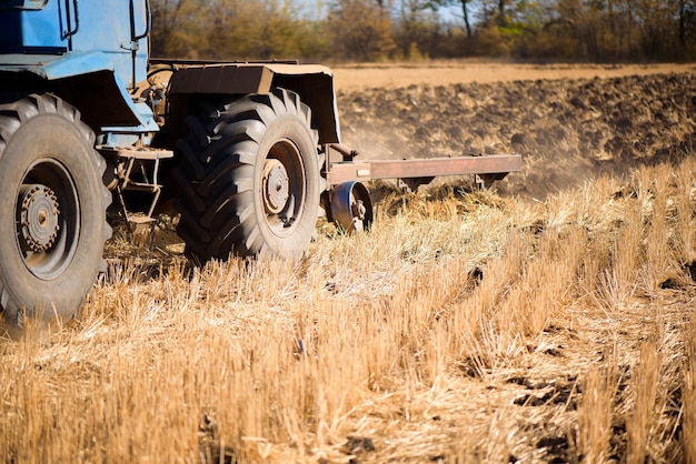 Tracteur agricole bleu labourant en automne sur le terrain.