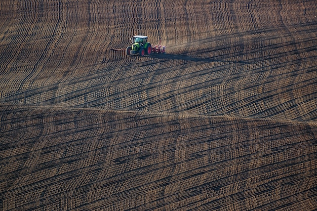 Tracteur agricole manipule la terre sur le terrain - préparation des terres agricoles pour les semis, paysage agricole