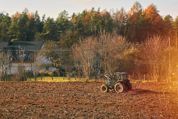 Tracteur agricole sur le terrain du sol zone rurale occupée paysagiste travaillant pendant les heures d'or