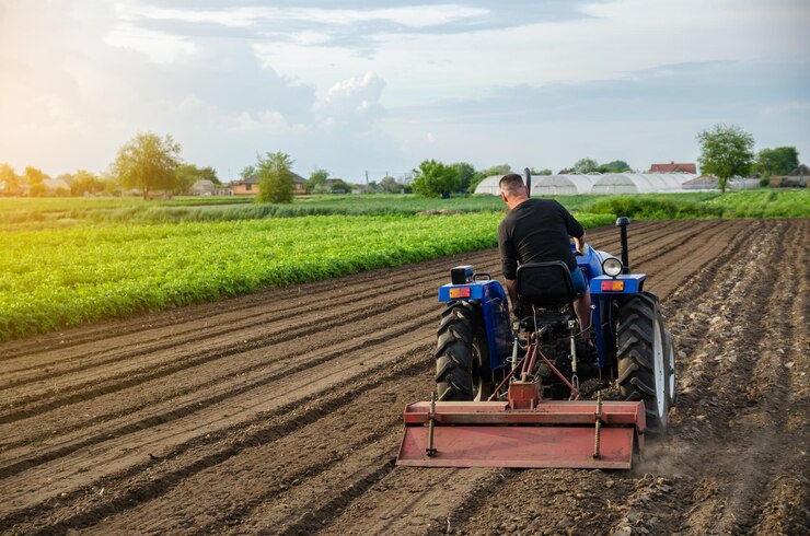 Photo un tracteur agricole travaille le sol d'un champ agricole, broyant le sol, écrasant et relâchant le sol.