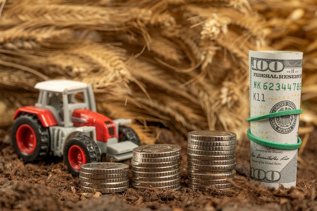 Tracteur avec de l'argent sur fond d'épillets de blé Exportation de céréales et agriculture Hausse des prix des produits agricoles