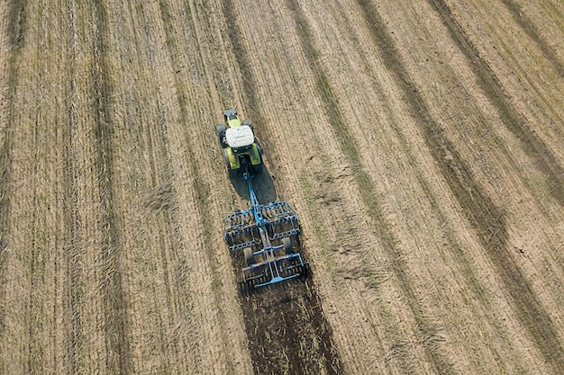 Tracteur au travail, cultivant un champ, vue aérienne du cultivateur de lit de semence.