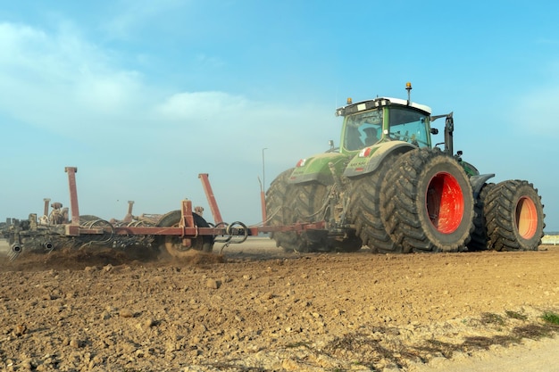 Tracteur avec une charrue travaillant dans le champ Un agriculteur conduisant un nouveau tracteur moderne laboure la terre Champ labouré proprement et en douceur Le début de la saison agricole La culture des céréales