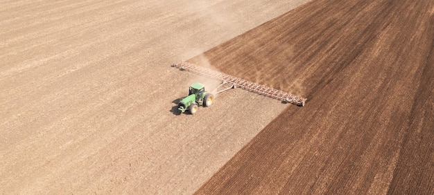 Un tracteur dans le champ cultive le sol avant le début de la campagne de semis Vue de drone