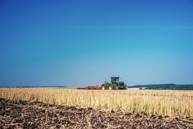 Tracteur labourant le champ de la ferme en préparation pour la plantation de printemps