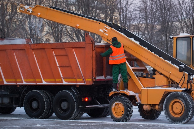 Tracteur nettoyant la route de la neige. La pelle nettoie les rues de grandes quantités de neige en ville. Les travailleurs balaient la neige de la route en hiver.