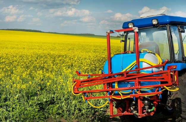 Tracteur pulvérisateur fermier près des champs de colza