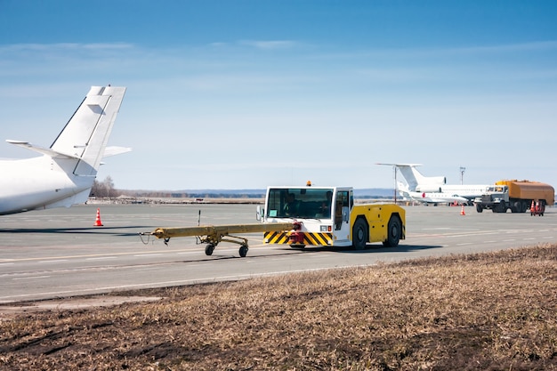 Photo tracteur de remorquage avec barre de remorquage et ravitailleurs d'avions pour camions-citernes se déplace sur le tablier de l'aéroport