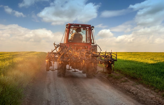 Tracteur sur la route après avoir travaillé à la ferme au coucher du soleil Silhouette d'un vieux tracteur sur une route de campagne sur le chemin du retour